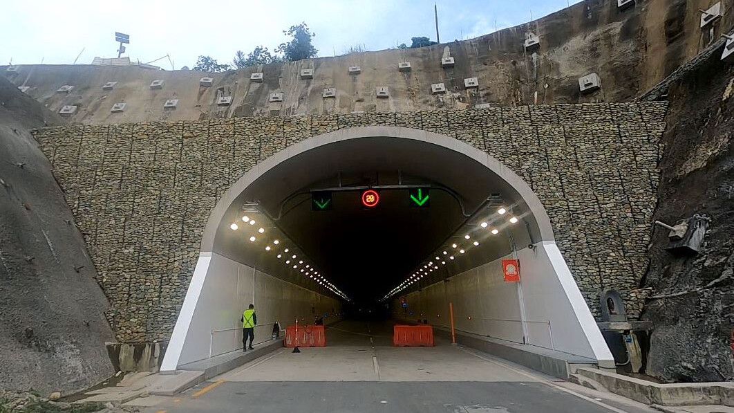 Ein Mann geht durch einen Tunnel mit Steinmauer.