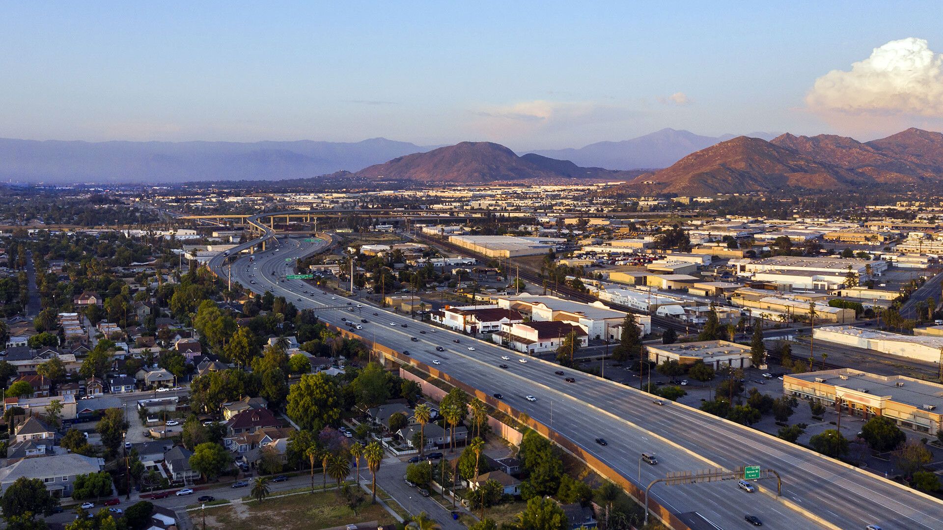 © Kapsch TrafficCom Luftaufnahme einer Autobahn in einer Stadt mit umgebenden Gebäuden und Bergen im Hintergrund.