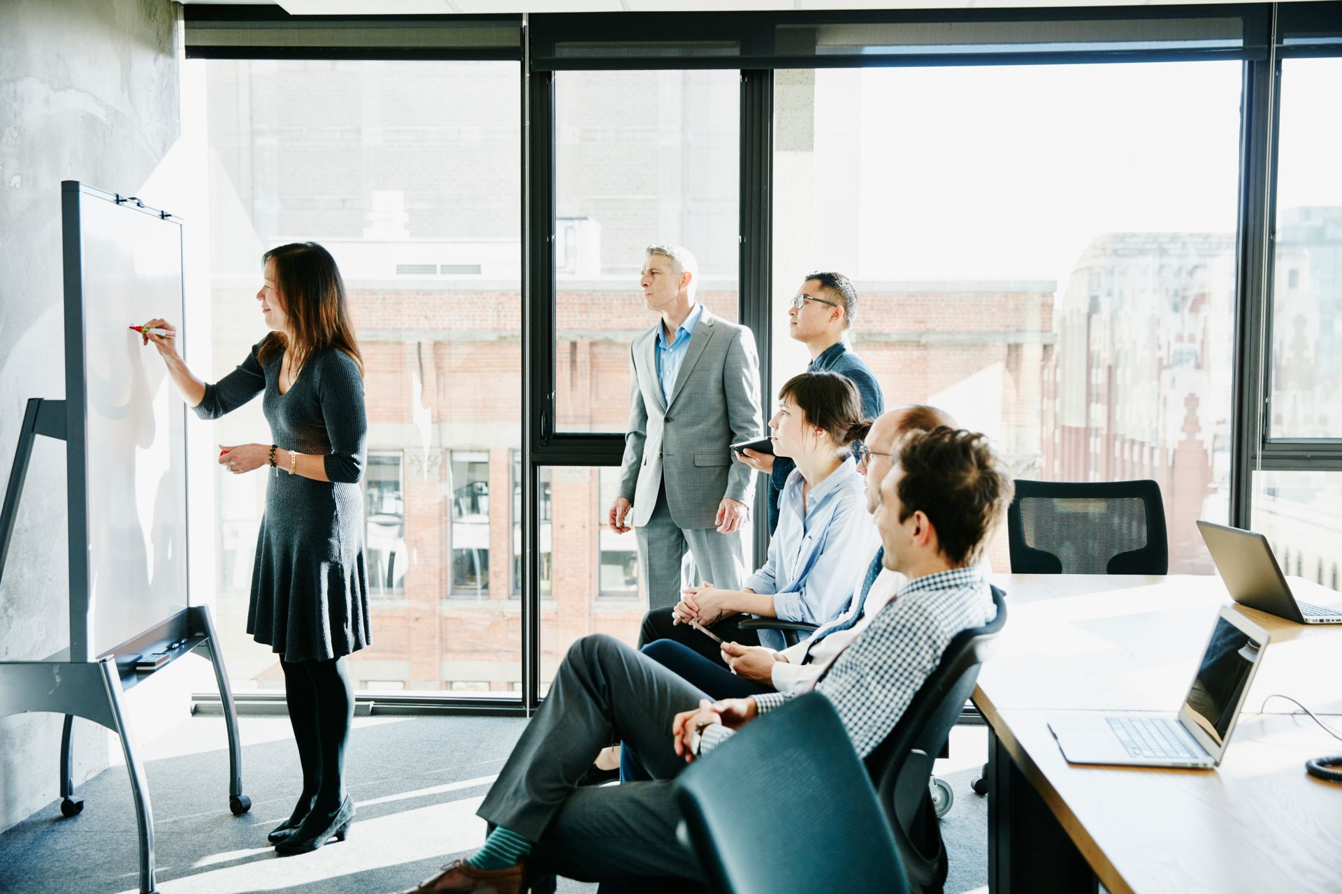 A woman leading a discussion at a Kapsch TrafficCom event, standing in front of a group of people.