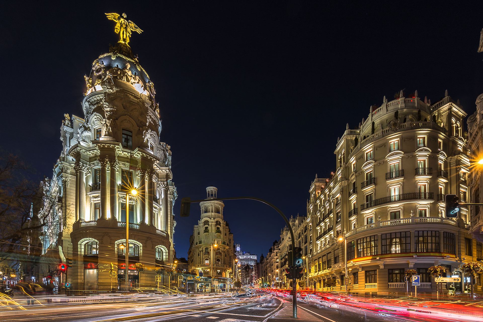 Eine Straße mit einem Gebäude und einer Statue auf dem Dach bei Nacht.