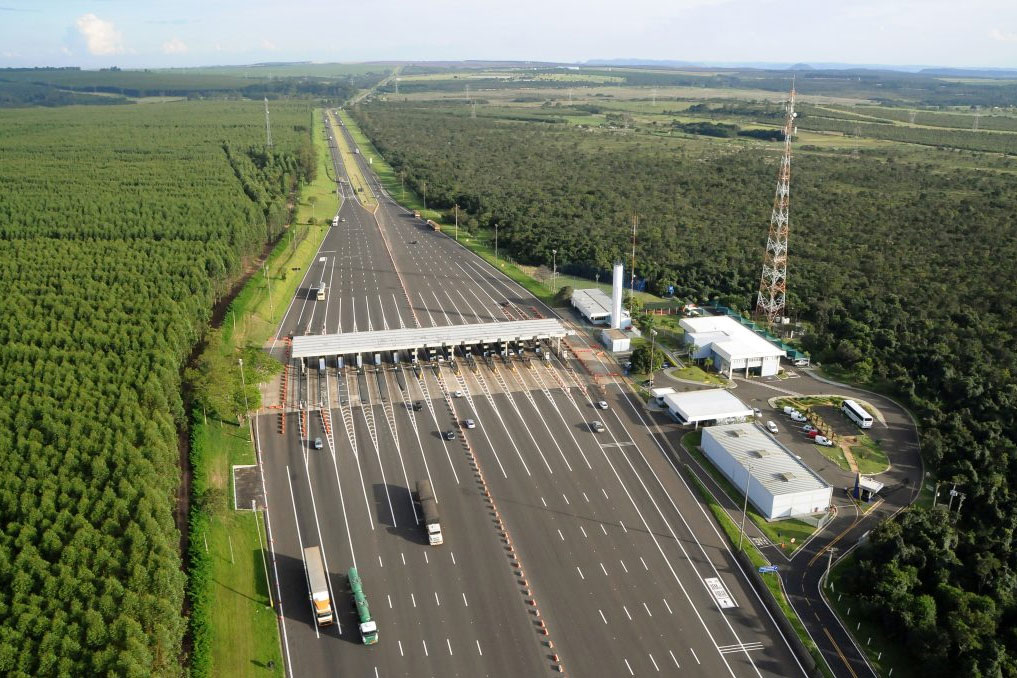 Luftaufnahme einer Mautstelle auf einer Straße mit mehreren Fahrspuren und Fahrzeugen.