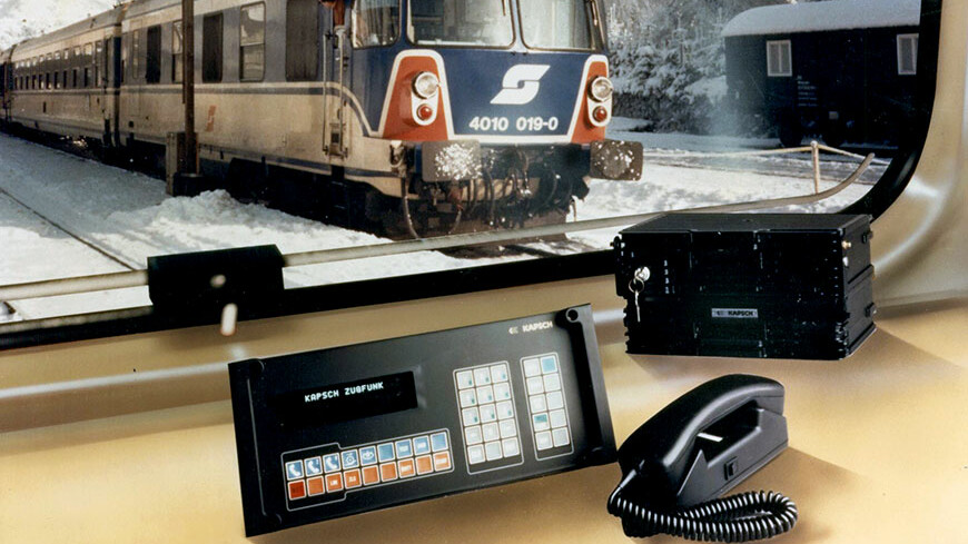 Ein Telefon und ein Zug auf einem Tisch, symbolisierend Kapschs historische Rolle in der Telekommunikation und im Eisenbahnsektor.