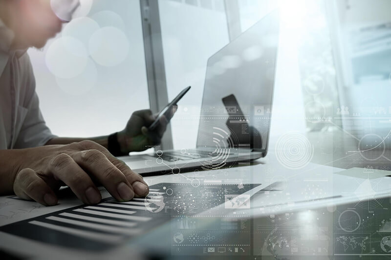 Eine Person benutzt einen Laptop und ein Telefon.