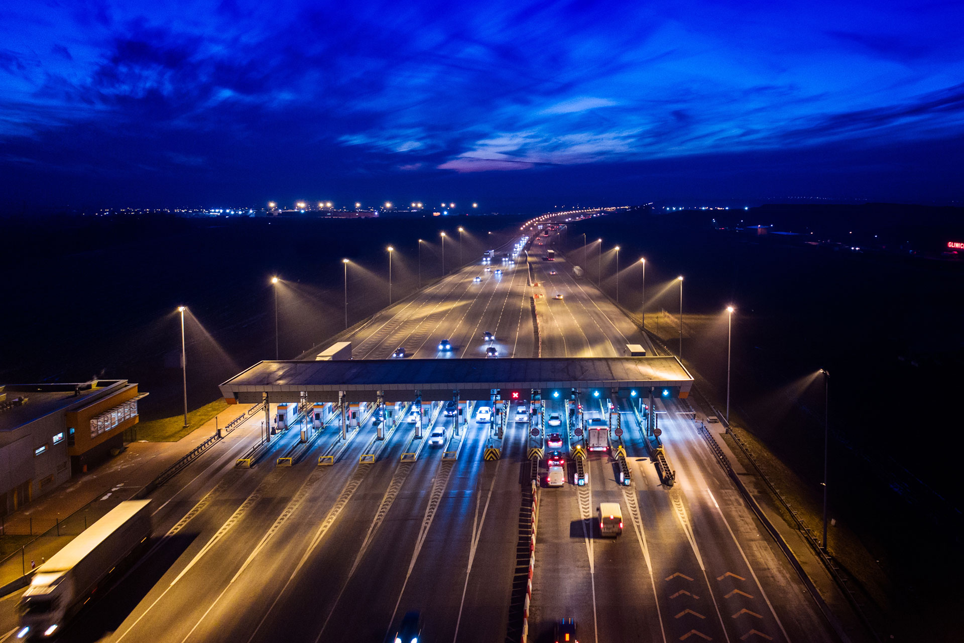 A toll booth at night with illuminated signage, emphasizing Kapsch's Tolling as a Service components.