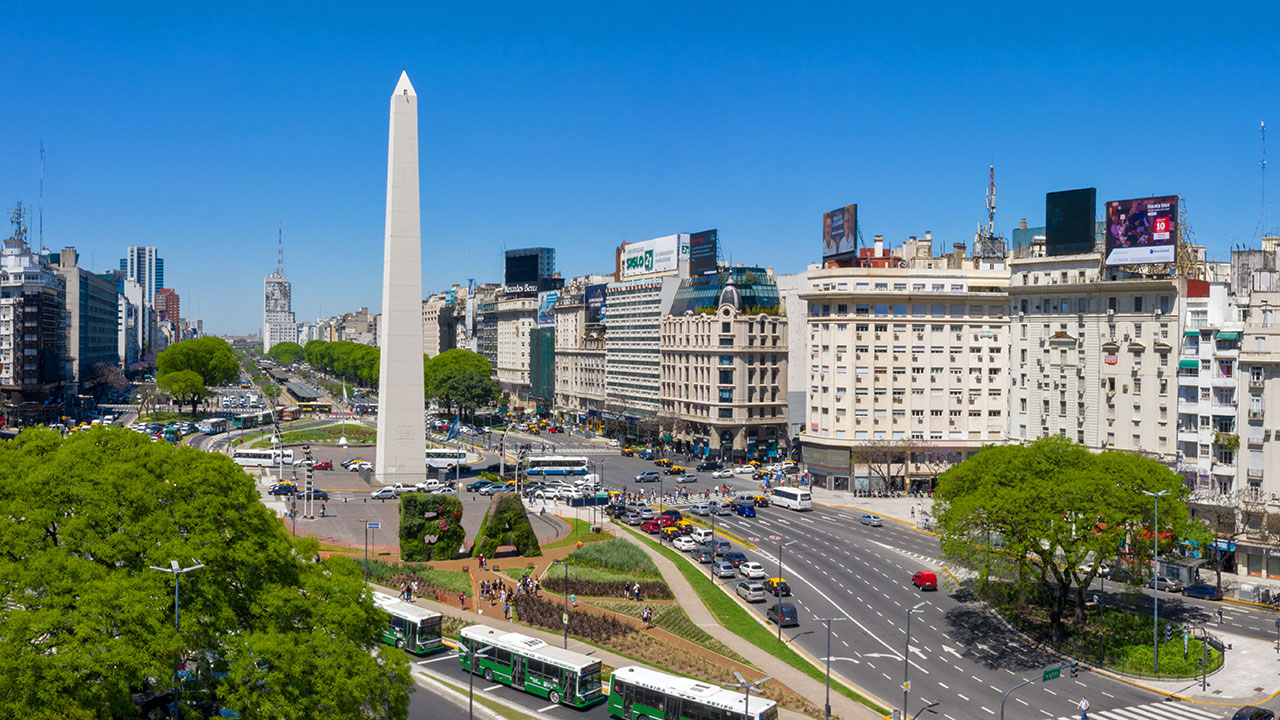 Straße mit dem Obelisco de Buenos Aires, umgeben von Bussen und Autos.
