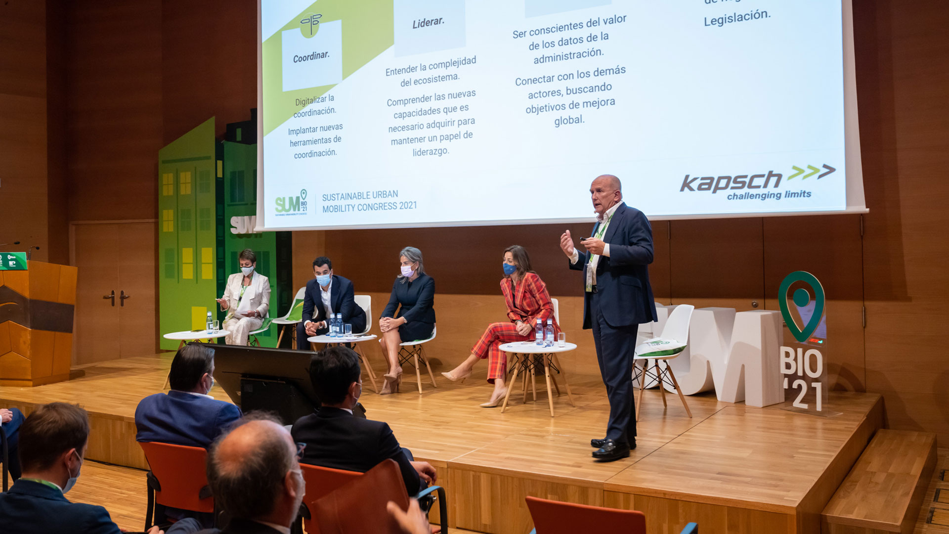 Eine Gruppe von Menschen sitzt auf einer Bühne während einer Präsentation.