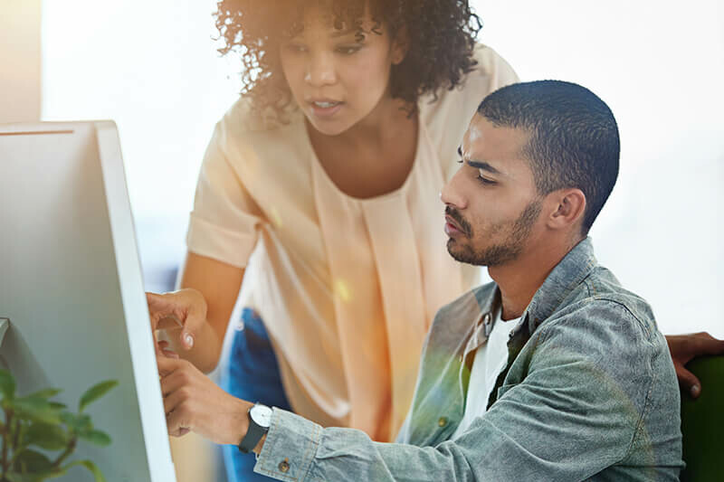 Ein Mann und eine Frau schauen auf einen Computerbildschirm.