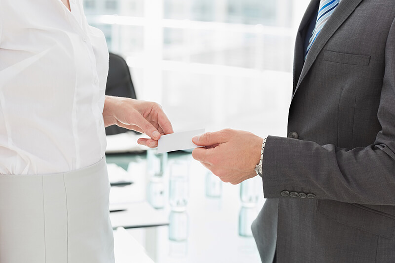 Ein Mann überreicht einer Frau eine Visitenkarte.