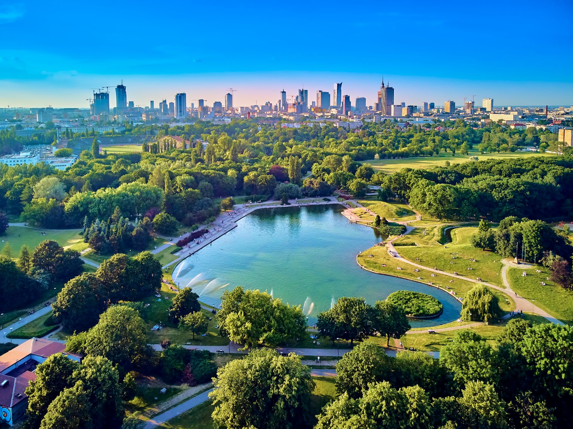 Ein Park mit einem Teich und einer Stadt im Hintergrund.