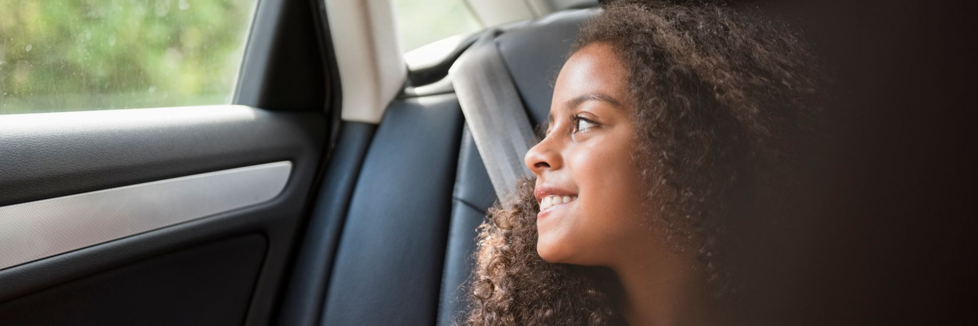 Ein Kind in einem Auto, die aus dem Fenster schaut, symbolisiert die Vision und Mission von Kapsch TrafficCom für innovative Mobilitätslösungen.